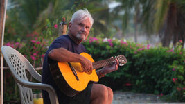 Corky Carroll playing accoustic guitar